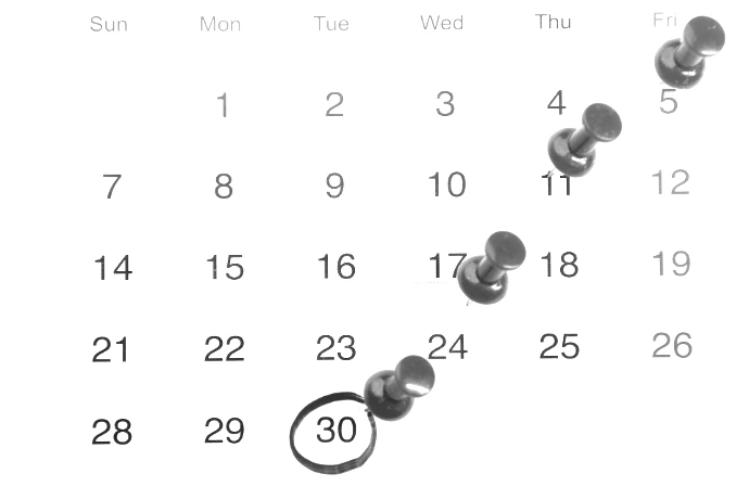 a calendar with red push buttons pinned to it